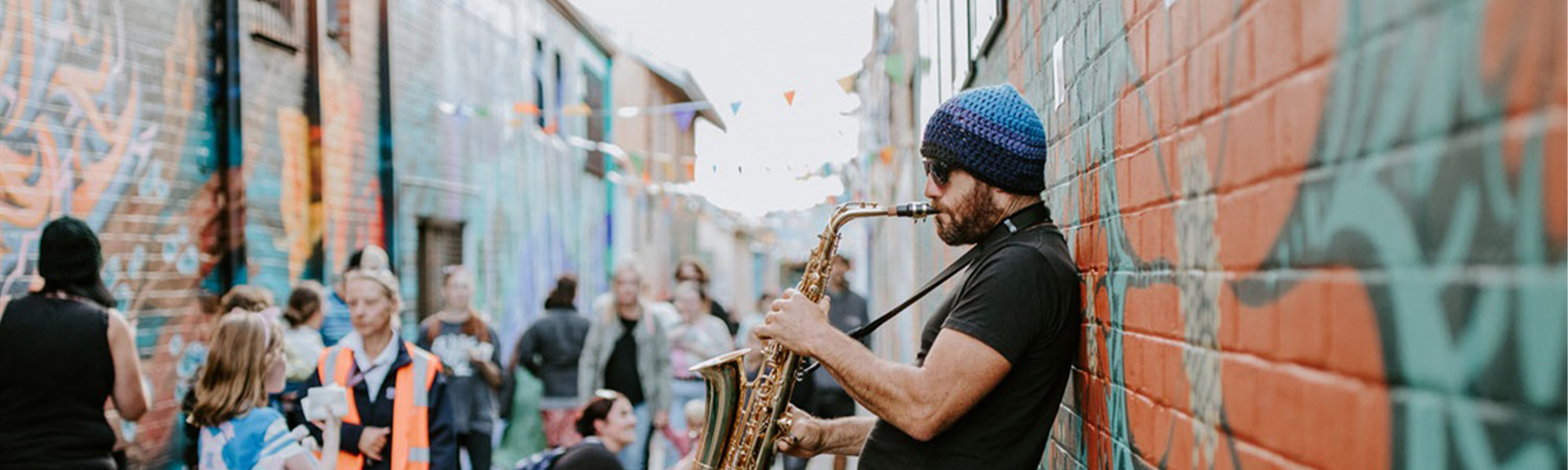 a man playing a saxophone in a painted laneway