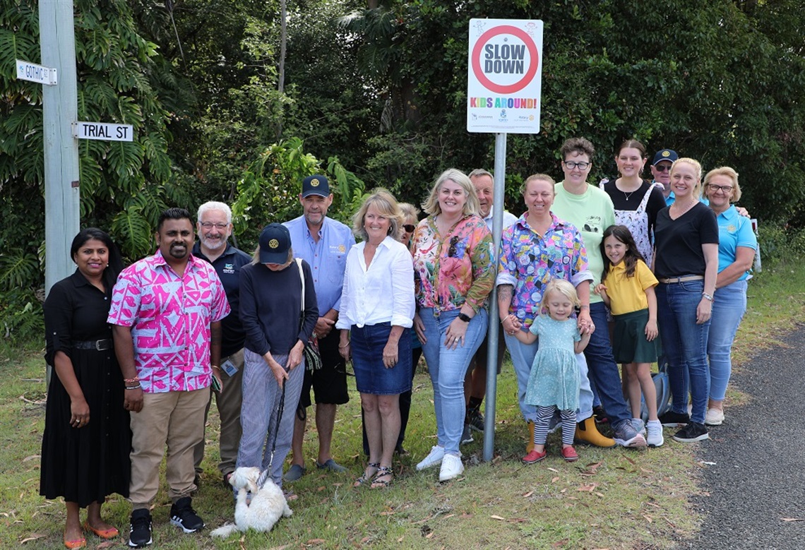 people standing in front of a road safety sign