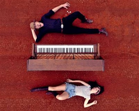boy and girl laying down beside a piano