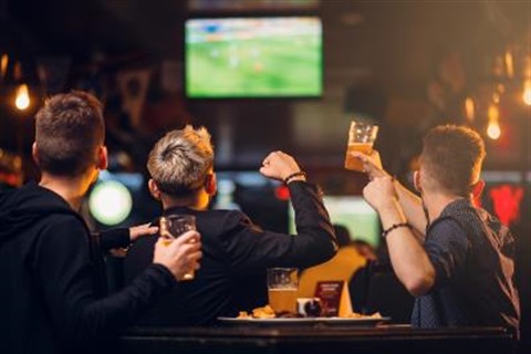men with drinks in front of tv screen